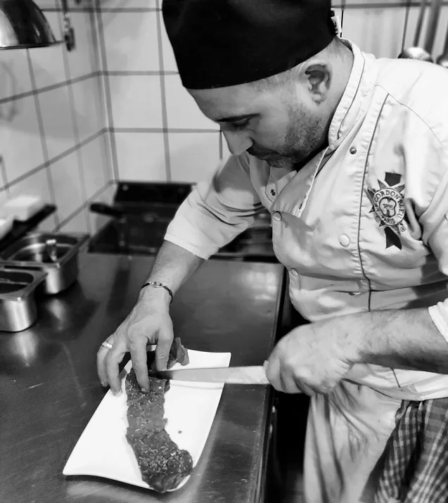 The chef of Le Petit Gourmet plating in the kitchen